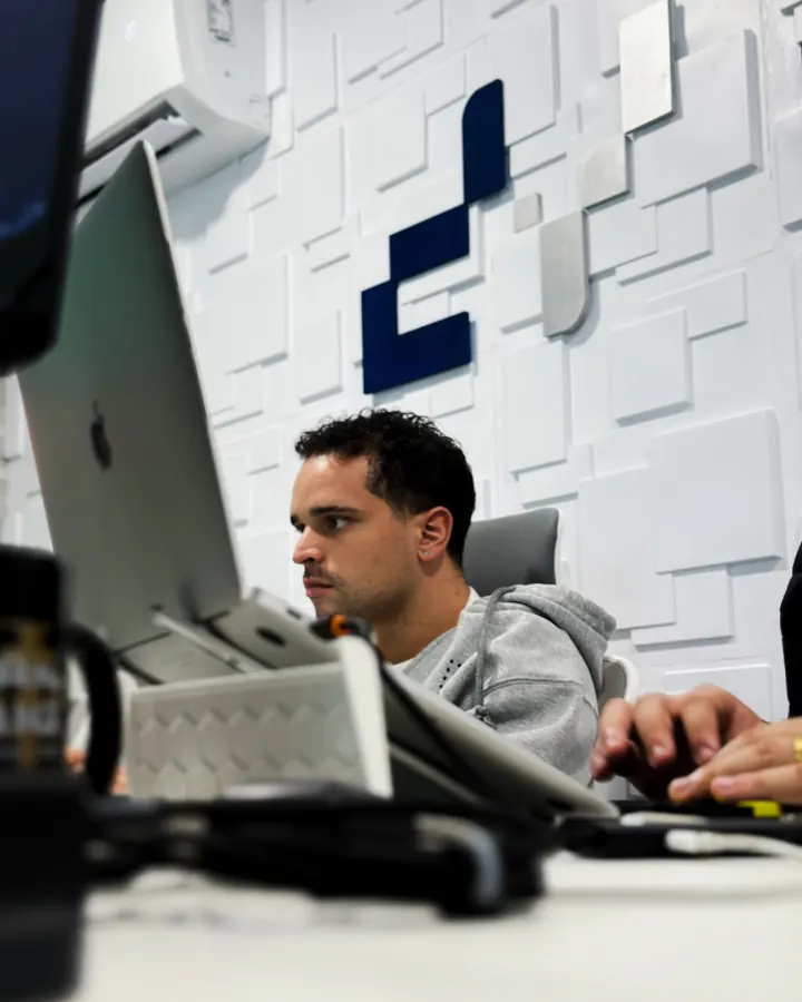 Desenvolvedor da Dyna Tecnologia programando com a identidade visual da empresa ao fundo